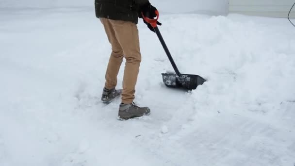 Man with a shovel removes snow. cleaning the area near the house after a snowstorm — Stock Video