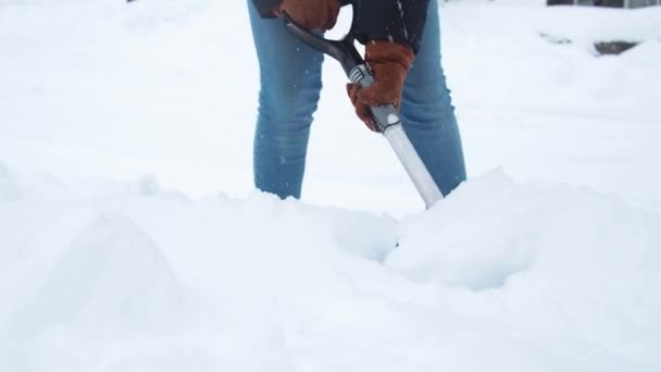 Una mujer con una pala quita la nieve. limpieza de la zona cerca de la casa después de una tormenta de nieve — Vídeos de Stock