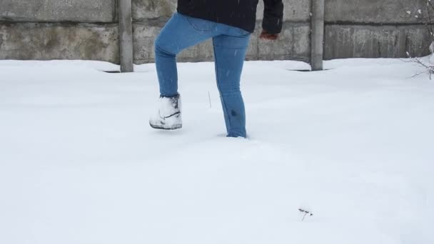 Benen går på snö med fotspår. Kvinnan banar väg genom ett snöfält. — Stockvideo