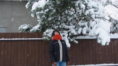 Karla kaplı çam ağacının altında duran bir kadın dallara tırmanıyor ve üzerine bir çığ düşüyor. Yavaş çekim