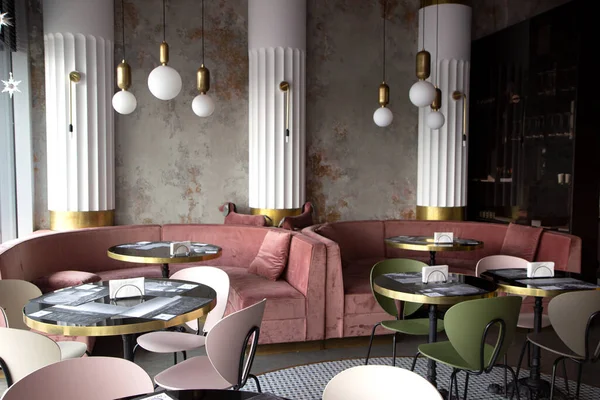 Modern tarzda, dokulu duvarları ve parketi olan bir restoran. Masalı yeşil ve pembe kanepeler var. Tavanda yuvarlak uzun ışıklar var. Minsk, Belarus - 20 Juny 2020