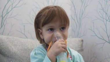 Hasta çocuk yüzünde maskeyle solunum yapıyor. Bebek nebulizörle soluyor.