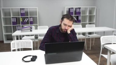 Uykulu adam iş yerinde uyuyor. Yorgun adam neredeyse sandalyeden düşüyordu. Sakallı adam birlikte çalışmaya çalışıyor.