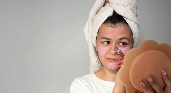 Cuidado de la piel facial en el hogar concepto. Mujer joven y feliz aplicando una máscara rosa en su cara con un cepillo — Foto de Stock