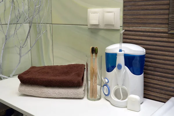 Eszközök fogmosáshoz a fürdőszobában. Öntözőgép és fogselyem bambusz öko fogkefével. Zéró hulladék, fenntartható fürdőszoba és életmód — Stock Fotó