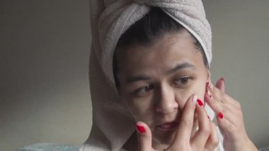 Kafasında havluyla üzgün bir kadın aynaya bakar ve cilt sorunu yüzünden stresli hisseder, endişeli kız dokunuşu yüzünden sinirli siyah nokta sivilcesi yüzünden sinirli
