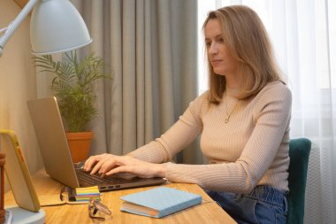 Bilgisayarlı orta yaşlı öğrenci çalışması ve notlar. Kadınlar dil öğrenir. Ders dinlerler. Evde web seyri izlerler.