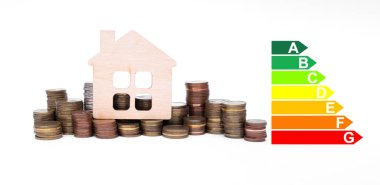 Bir yığın bozuk para ve ev modeli enerji verimliliği derecelendirme evini gösteriyor. Para biriktirmenin açık bir örneği