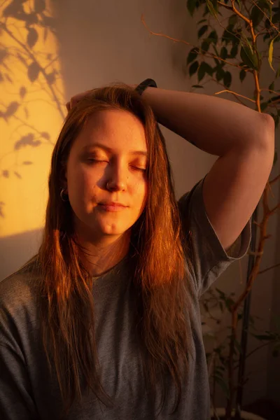 Jovem mulher fechar os olhos e relaxamento em raios quentes de pôr do sol. Calmo retrato quente da menina interior. — Fotografia de Stock