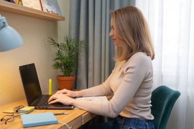 Middle age student study online with laptop and write notes. Women learn language listen lecture watch webinar