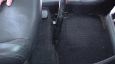 Adam elektrikli süpürgeyle kirli araba temizliyor.