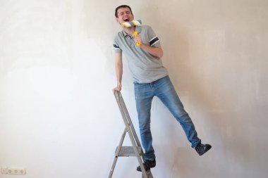 Paten fırçasını mikrofon olarak kullanan mutlu bir beyaz adam şarkı söylüyor. Genç erkek ev tamiri ve yenileme odasında eğleniyor.