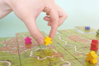 El ve çip oyun sahasının altında. Carcassonne oyun kartları ve fişler masaya yakın. Masa oyunu ve eğlence konsepti. Minsk, Belarus - 10 Temmuz 2021