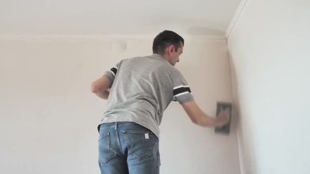 男人在墙上用砂纸把坚硬的油灰磨平 专业维修男性装修公寓 — 图库视频影像