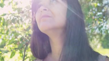 Bir ağacın çiçek açan dalında kadın portresi. Genç ve güzel bir kadın bahçedeki çiçeklerin kokusunu seçici bir odak ile alır.