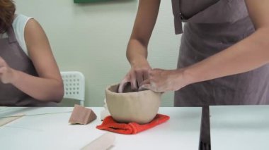 Çömlekçi kadın çömlek atölyesinde kilden kupa yapıyor. Seramik bardak oluşturma süreci. El yapımı, hobi sanatı ve el işi konsepti