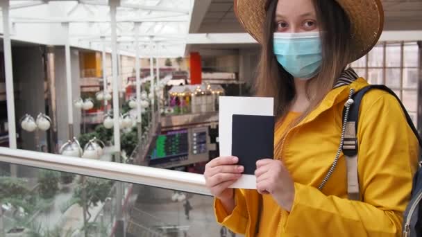 Jonge moderne toeristische vrouw in het geel met gezicht medisch masker op de luchthaven of het station. Reizen tijdens de coronavirus pandemie en toerisme na het einde van quarantaine covid 19. nieuwe normale. — Stockvideo