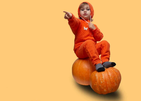 Kid Girl Orange Suit Sits Pumpkins Points Finger Copy Space — Stock Photo, Image