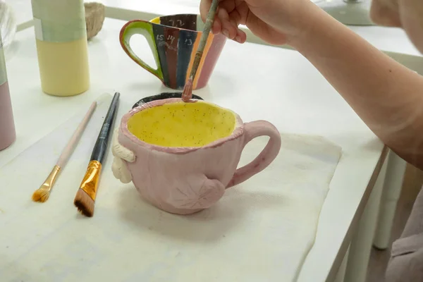 陶瓷工作室里的小女孩用毛刷在陶瓷杯上作画。儿童艺术和绘画的发展 — 图库照片