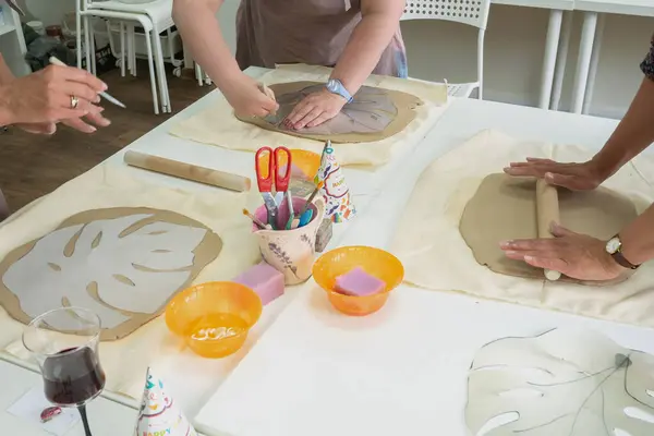 Kadın seramik atölyesinde ahşap merdane kullanarak kil yuvarlıyor. Eller yakın çekim. Çömlek oluşturuluyor — Stok fotoğraf