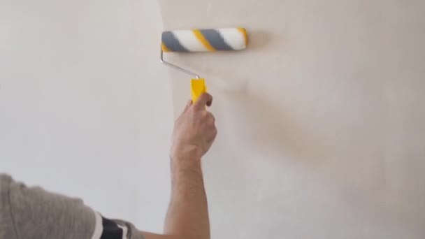 Hombre cebando la pared con un rodillo. Reparación del interior. Joven decorador masculino pintando una pared en la habitación vacía. Concepto renovación hacerlo usted mismo. — Vídeo de stock