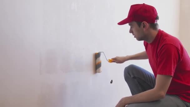 Un uomo che attacca il muro con un rullo. Riparazione degli interni. Giovane decoratore di sesso maschile che dipinge un muro nella stanza vuota. Concetto rinnovamento fai da te. — Video Stock