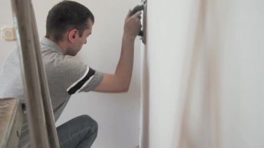 Adam duvardaki sert macunu düzeltti. Zümrüt bir kağıt. Profesyonel tamirci dairede tadilat yapıyor..