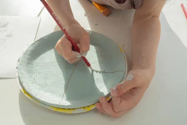 Kid handmålning med penna på färgad lera keramik kopp i keramik verkstad studio. Utveckling av konst och måleri hos barn. Närbild. — Stockfoto