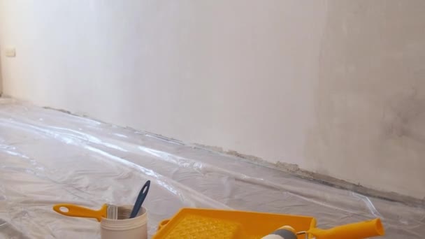 Ristrutturazione a casa. Primer o vernice in secchio e spazzole con rullo su sfondo muro di cemento. Riparazione in sala ristrutturazione. — Video Stock