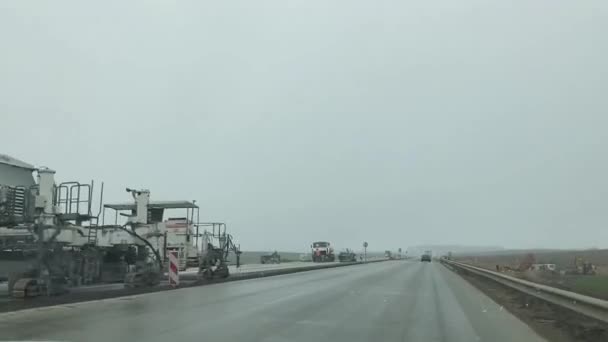 Punto de vista del coche que conduce más allá de las obras de reparación, maquinaria pesada de la planta en uso, se aplican restricciones de velocidad. Minsk, Bielorrusia - 4 de mayo de 2021 — Vídeo de stock