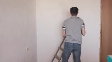 Adam duvardaki sert macunu düzeltti. Zümrüt bir kağıt. Profesyonel tamirci dairede tadilat yapıyor. 