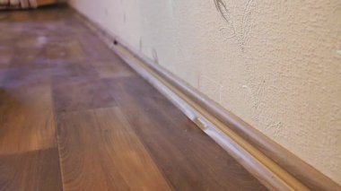 Elinde tornavida olan bir işçi dairedeki süpürgeliğin vidalarını söküyor. Kapat. Beyaz Rusya, Minsk - 9 Mayıs 2021