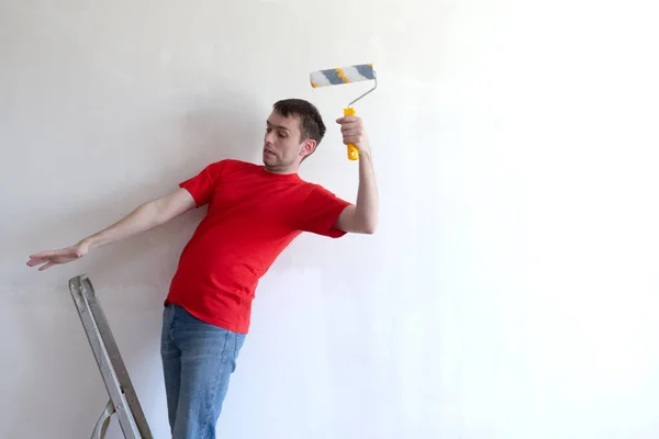Homme peint mur et tombe de l'échelle tout en faisant des réparations à la construction. assurance et menace pour la vie pendant la construction ou la rénovation. — Photo