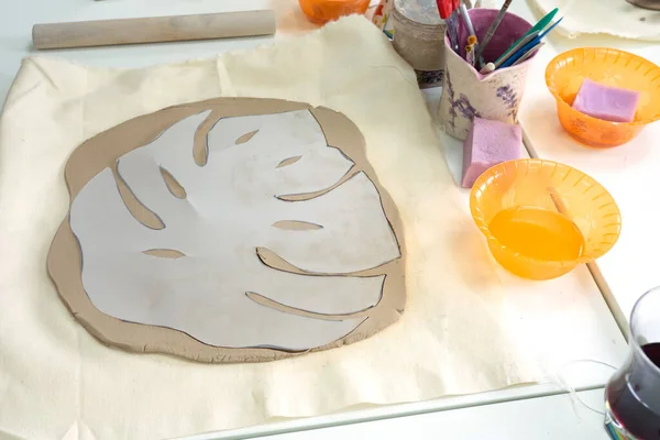 Woman hand potter making clay monstera leaf in pottery workshop studio. Process of creating ceramic vase. Handmade, hobby art and handicraft concept — Stock Photo, Image