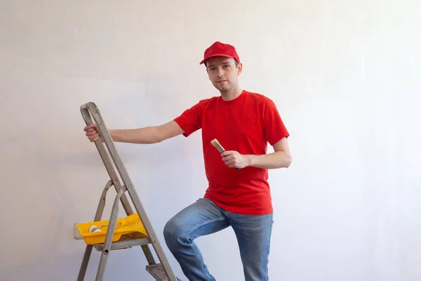 Nuori Professional korjaus mies harjalla maalaus tikkaat ja harmaa sementti seinään taustalla. — kuvapankkivalokuva