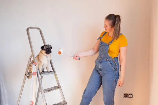 La mujer feliz hace reparaciones en su apartamento. Divertida hembra con un rodillo en escalera con espacio para copiar. Independiente mujer soltera. — Foto de Stock