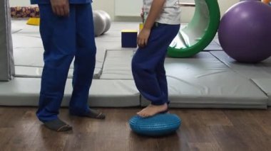 Terapisti olan çocuk duyusal bütünleşme sırasında dokunmatik ayak masajı aleti üzerinde egzersiz yapıyor. Duyusal işleme bozukluğu