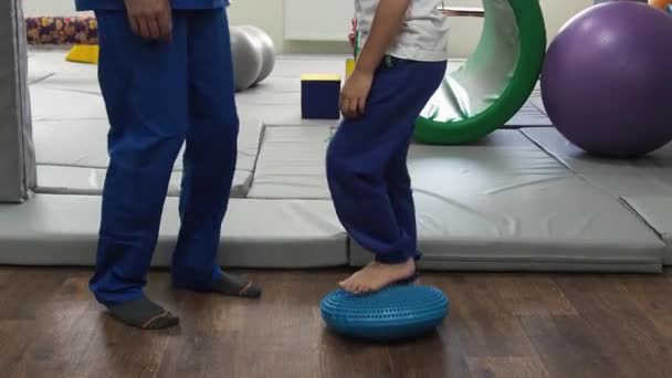 A kislány a terapeutájával tapintópad lábmasszírozón gyakorol az érzékszervi integrációs kezelés alatt. Érzékelési zavarok — Stock videók