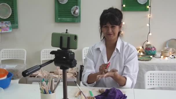 여고생 이 아트 스튜디오에서 도자기 온라인 강좌를 위한 동영상 강의를 녹화하거나 세라믹 제품을 만드는 강의 마스터 클래스를 이끌기도 한다. 점토 모형을 제작하는 비디오를 녹화하는 블로거. — 비디오