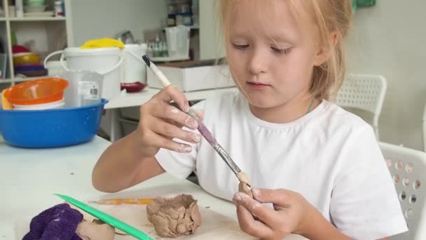 Klei modellenatelier. Kind meisje beeldhouwt uit klei in aardewerk werkplaats. Onderwijs voor creatieve activiteiten van kinderen in de kunsten. — Stockvideo