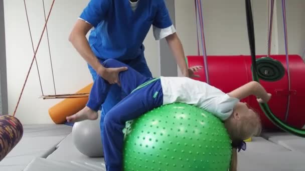 Дитяча дівчинка з фізіотерапевтом на м'ячі під час сеансу сенсорної інтеграції. Функції розвитку вестибулярного апарату у дітей . — стокове відео