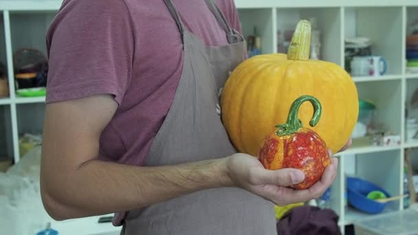 Homem comparar abóbora vegetal e abóbora cerâmica no estúdio de cerâmica. Símbolo de arte Halloween. — Vídeo de Stock