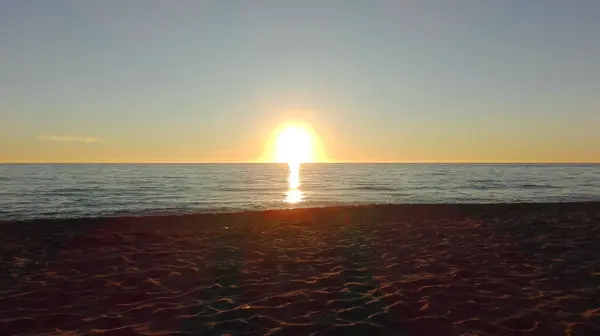 トスカーナのビーチで海の水の上の地平線に太陽のロマンチックな夕日 — ストック写真