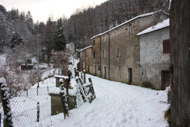 Beyaz karlı dağ tepelerindeki terk edilmiş köy Toskana 'daki ormanın tersine döndü.