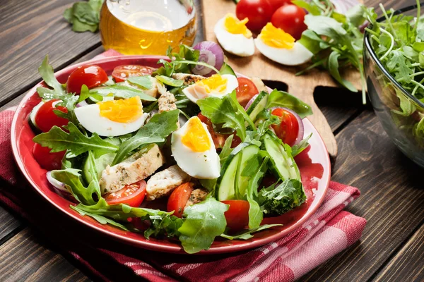 Salada fresca com frango, tomate, ovos e rúcula no prato — Fotografia de Stock