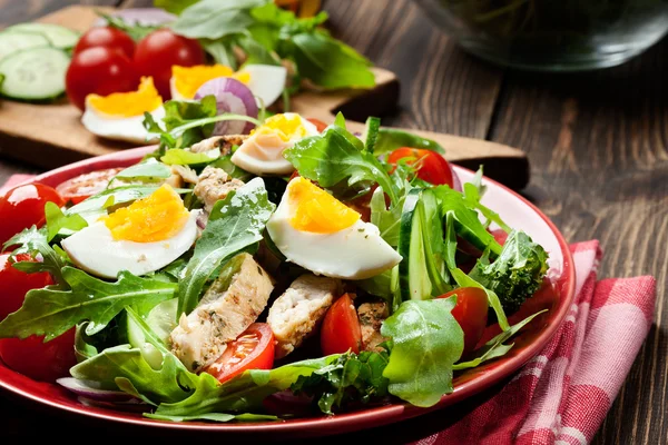 Salada fresca com frango, tomate, ovos e rúcula no prato — Fotografia de Stock