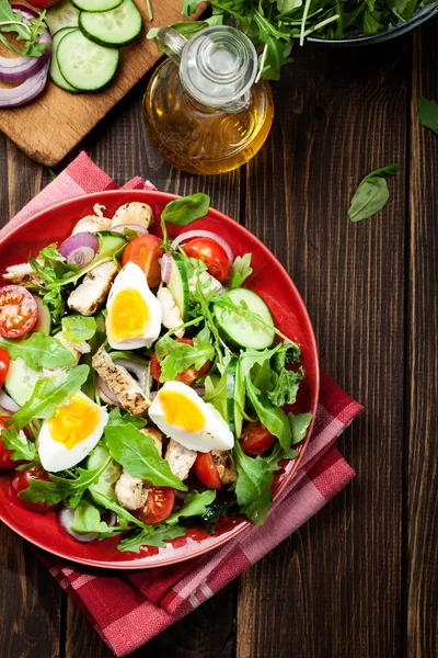 Čerstvý salát s kuřecím masem, rajčaty, vejce a rukolou na desce — Stock fotografie