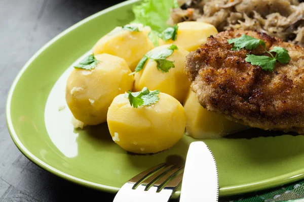 Boiled potatoes with fried pork schnitzel and fried sauerkraut — Stock Photo, Image