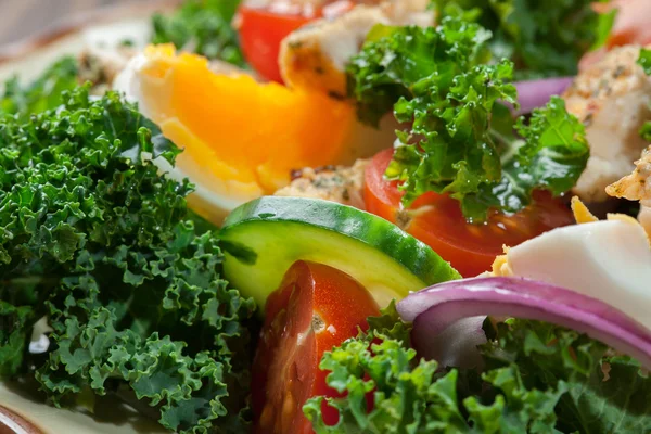 Свіжий салат з куркою, помідорами, яйцями та салатом на тарілці — стокове фото