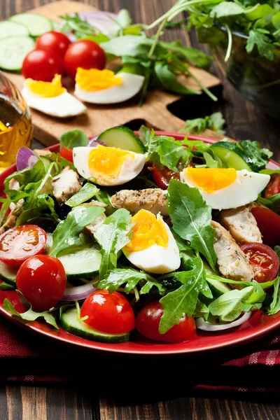 Frischer Salat mit Huhn, Tomaten, Eiern und Rucola auf Teller — Stockfoto